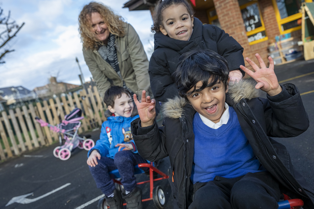 children and teacher playing in playground